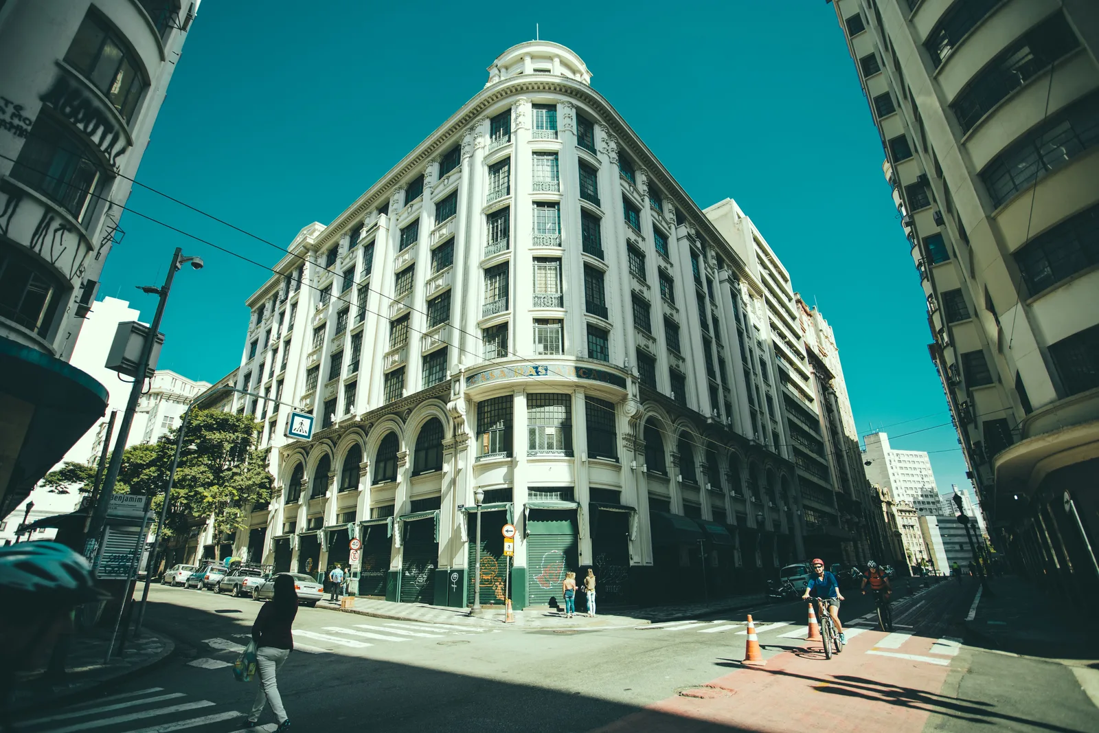 Wide-angle street corner view where the building edges splay and the facades stretch toward the frame