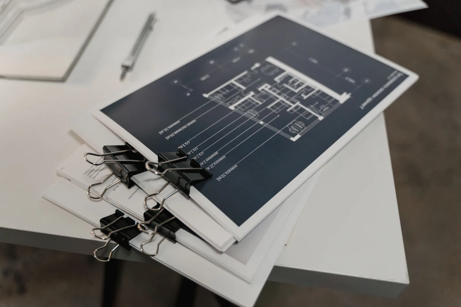 Stack of printed architectural drawing sets held together with black binder clips