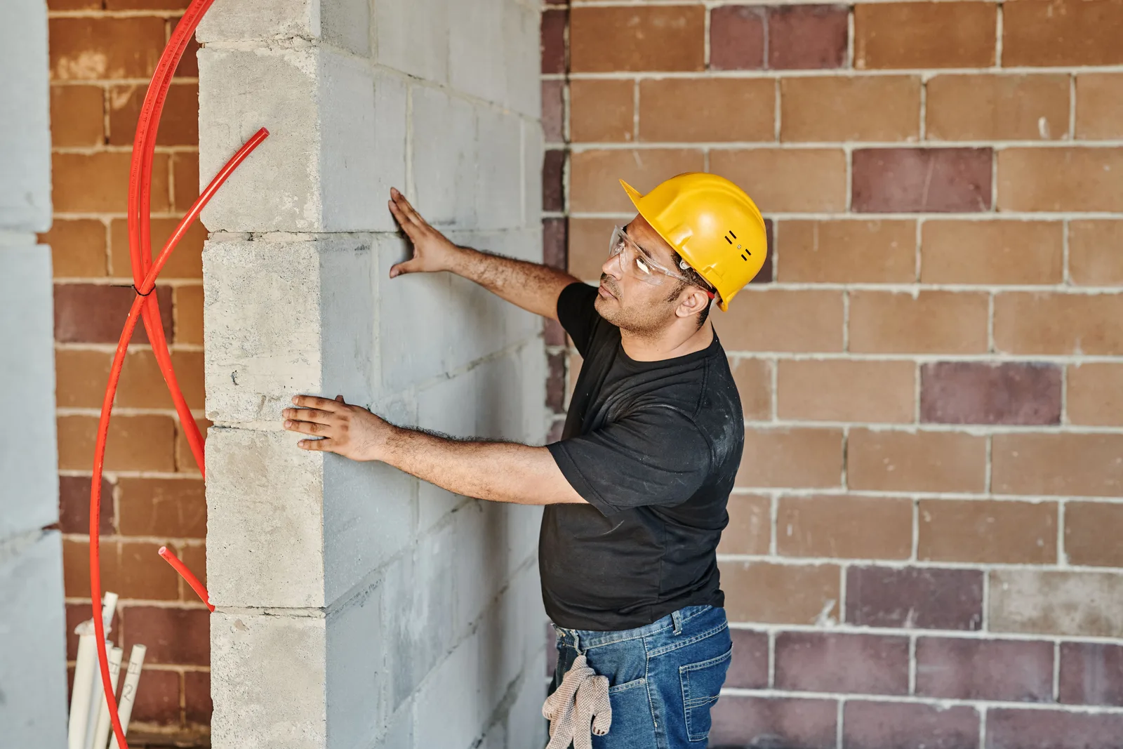Builder checking an aerated concrete block wall laid against an older brick wall