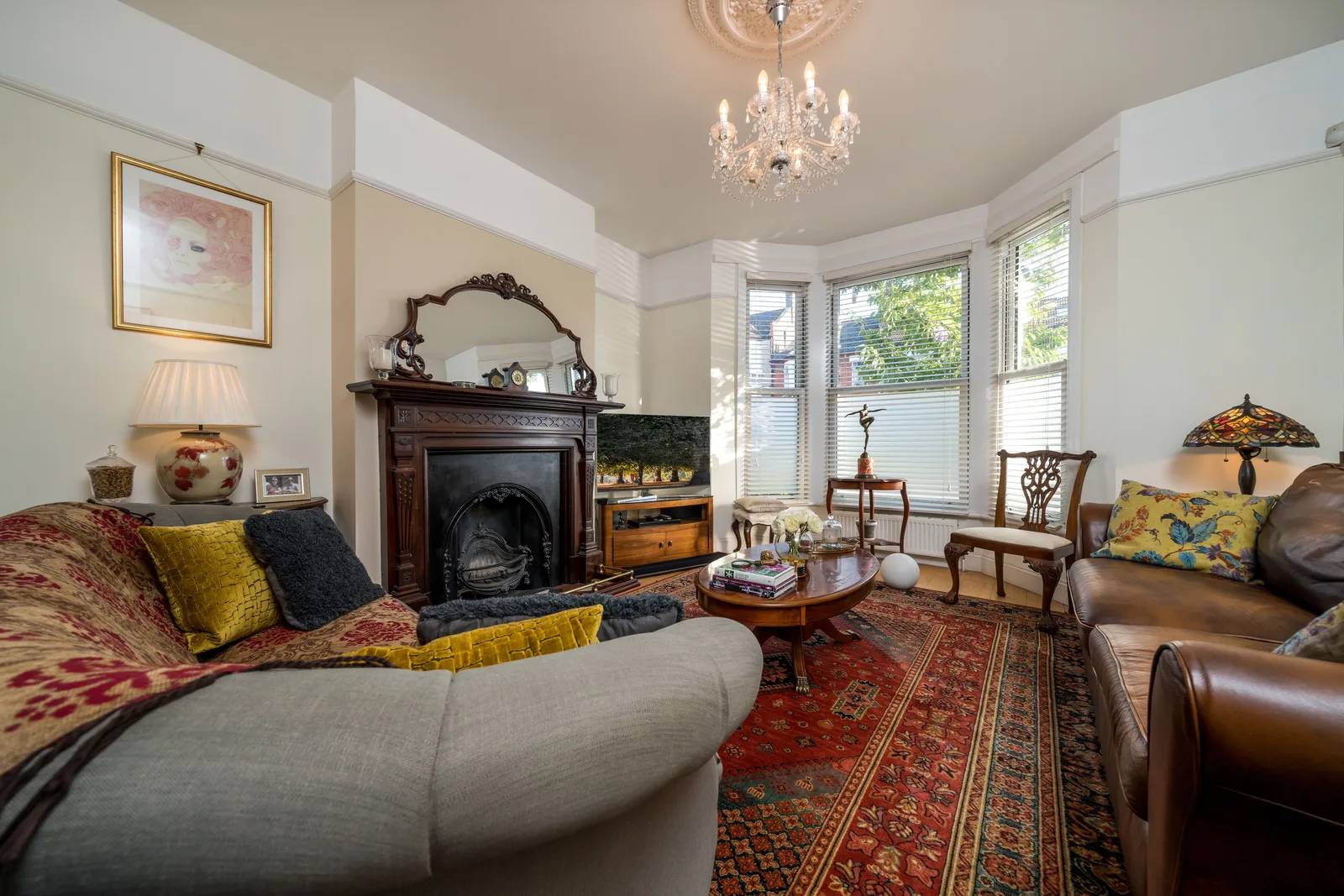 Traditional living room with cast iron fireplace, crystal chandelier, Persian rug and antique side chairs