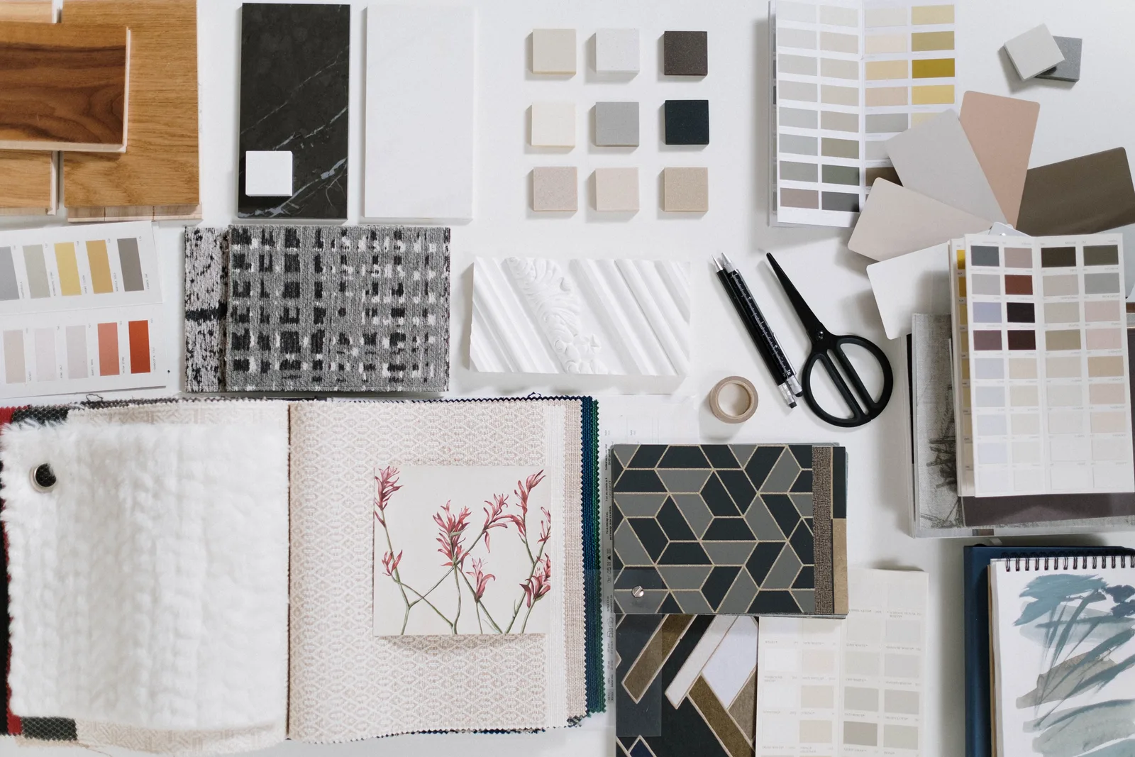 Flat lay of interior material samples: wood veneers, paint chips, fabric swatches, tiles and stone