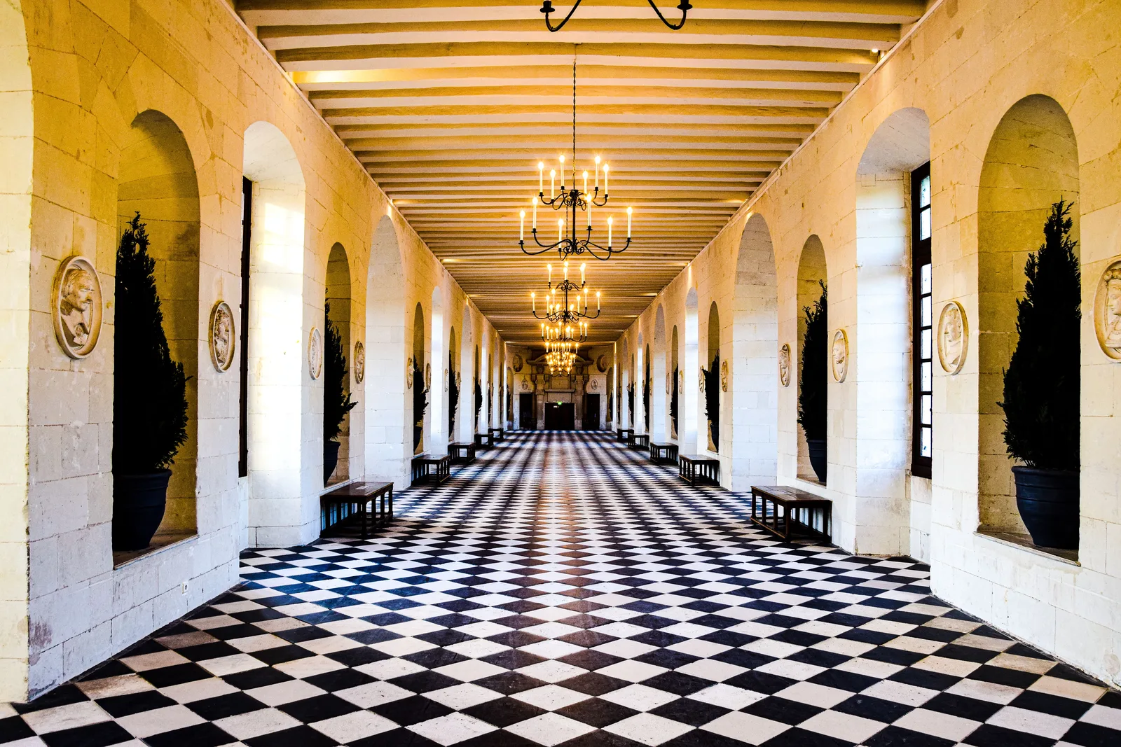 Long palace gallery with a checkered floor and ceiling beams converging on a single point at the far end