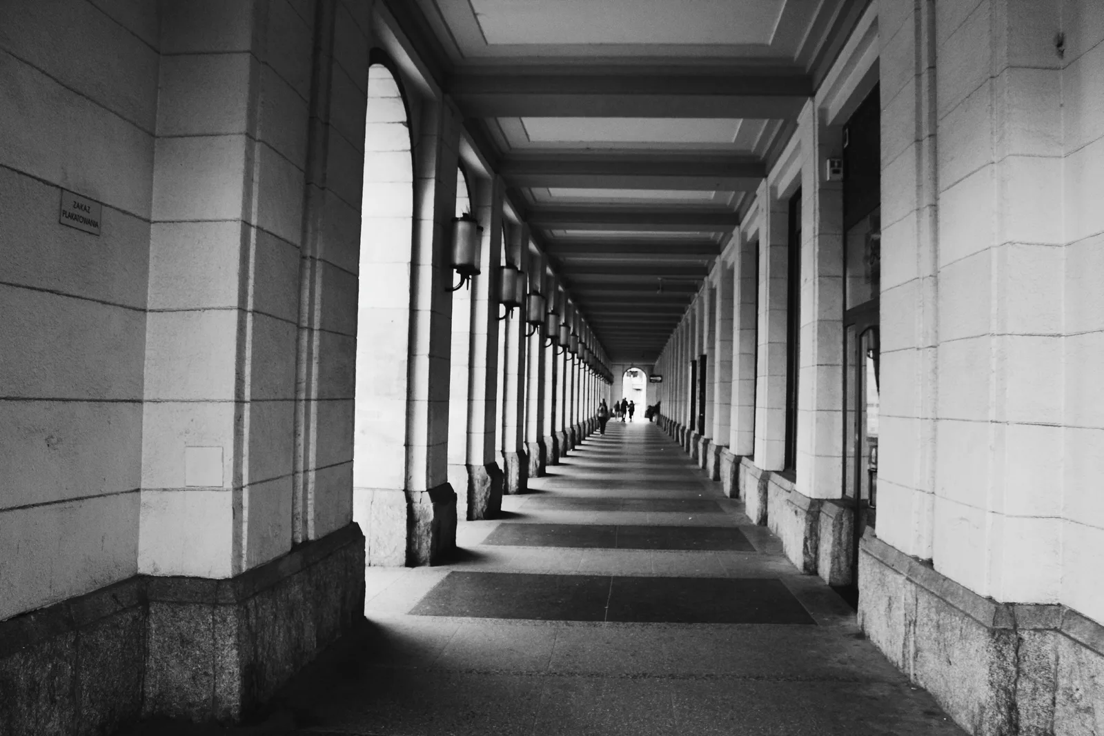 Black and white arcade with stone piers, its vanishing point set off-centre so the open side dominates