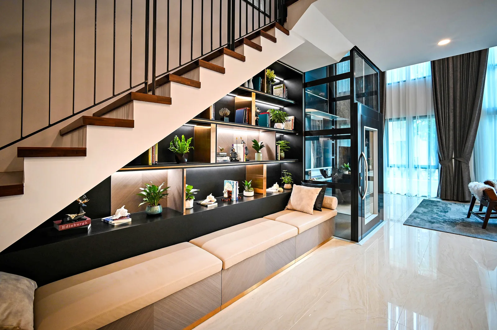 Built in bench and lit shelving tucked under a staircase, using the void below the treads as storage