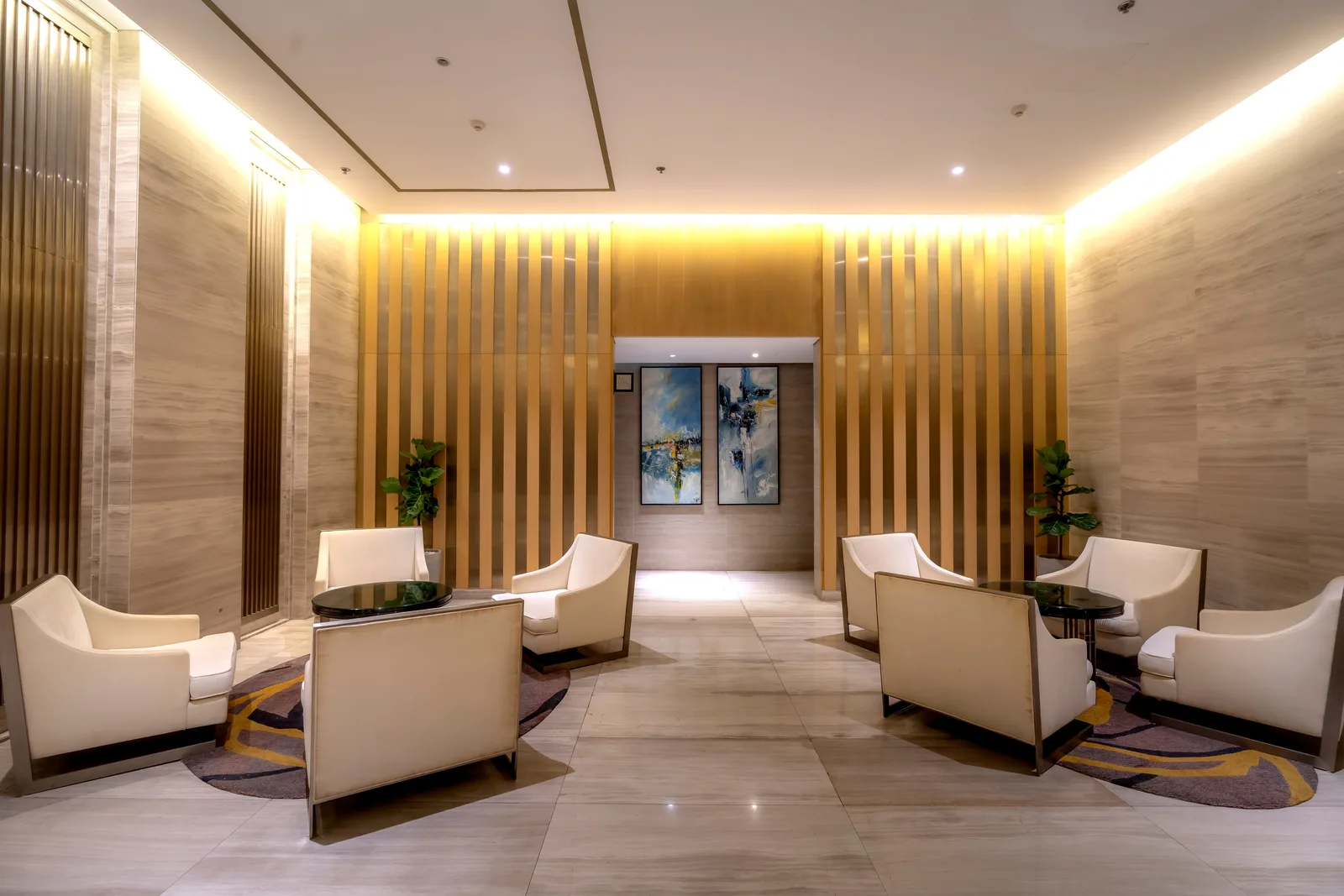 Hotel lobby with stone wall cladding, timber slats and warm cove lighting over lounge chairs